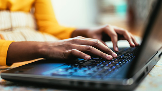 Close-up of hands typing on a laptop keyboard.
