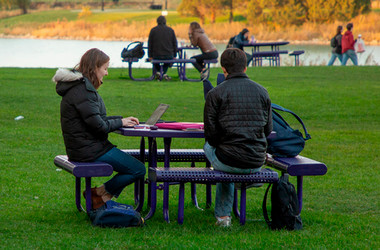 Students working on laptops behind Norris Student Center in the fall