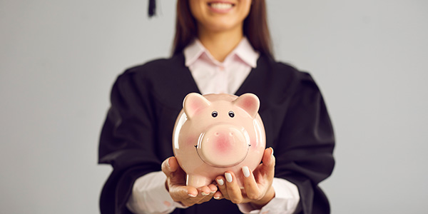 Graduate holding a piggy bank representing financial aid