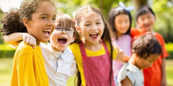 Multi-ethnic group of school children laughing and embracing